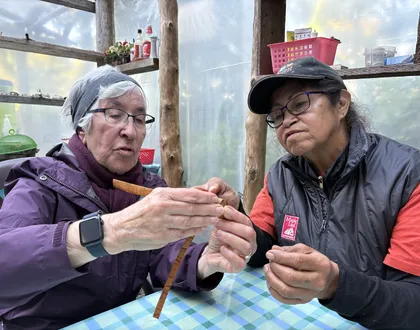 Bev Michel helping guest weave with cedar bark
